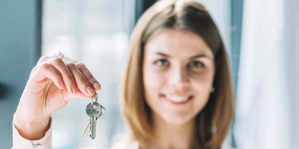 Mujer sonriente sosteniendo llaves de departamento nuevo